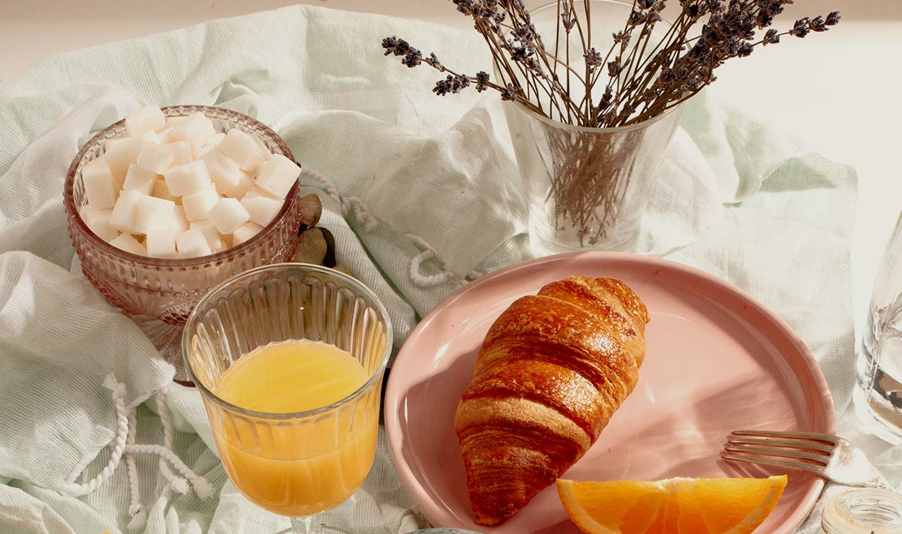 A place setting with a croissant and orange juice.
